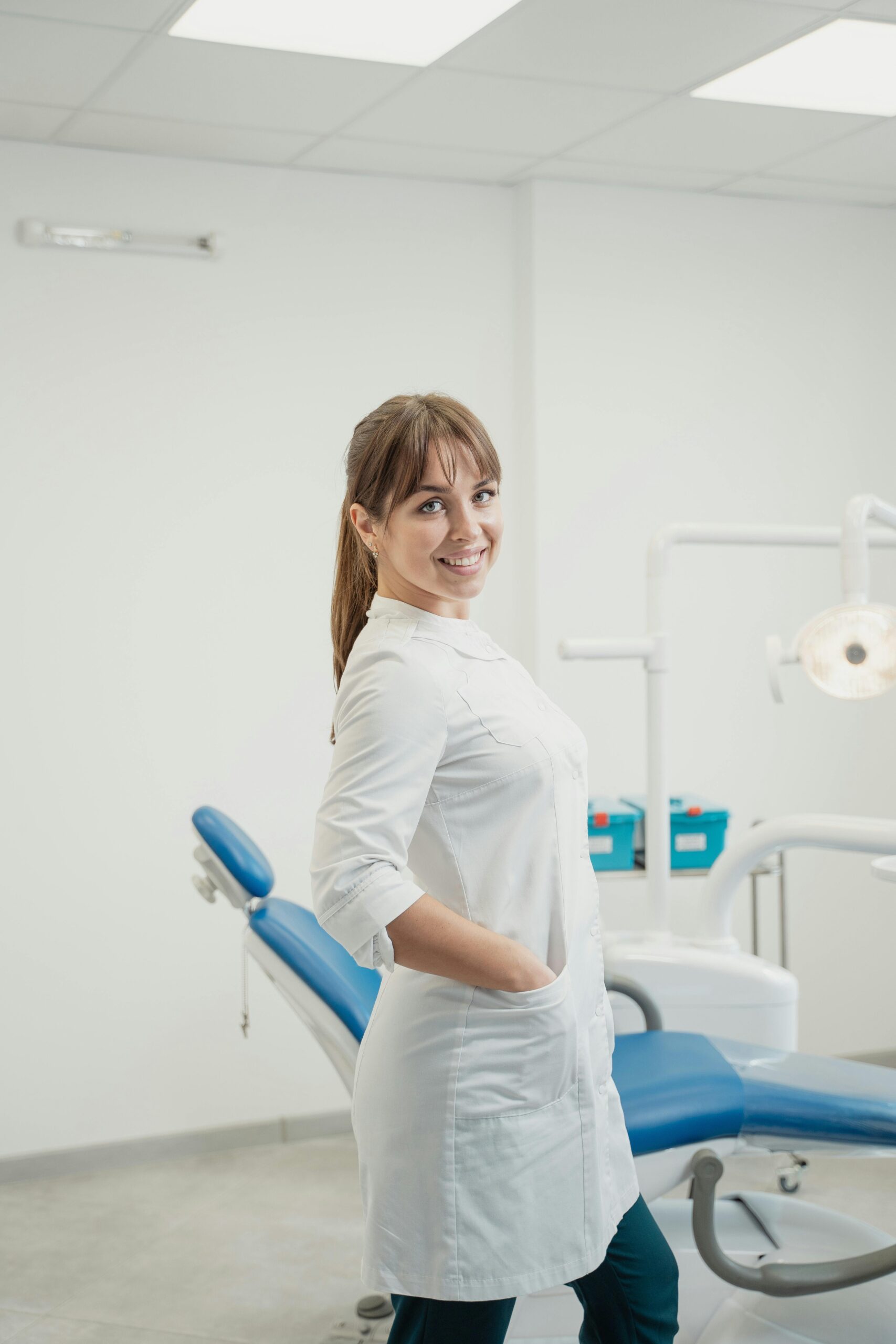 Smiling female medical professional posing in a modern dental clinic.